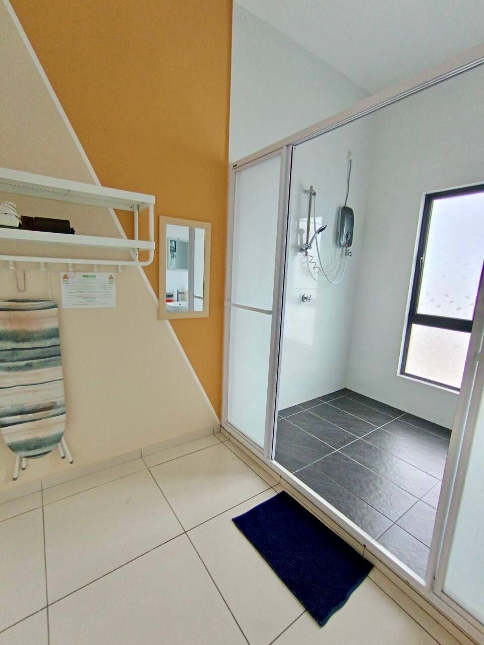 A bathroom with a shower, a towel rack, and a window.
