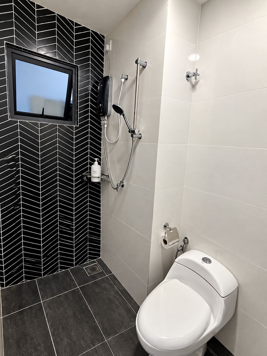 Een badkamer met toilet, douche en een televisie aan de muur.