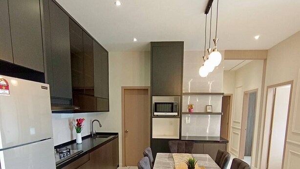 A modern kitchen with a dining area, featuring a refrigerator, stove, microwave, and a large dining table with chairs. - Skyline Suites l The Horizon Ipoh by Grab A Stay l 1-8pax (Ipoh)
