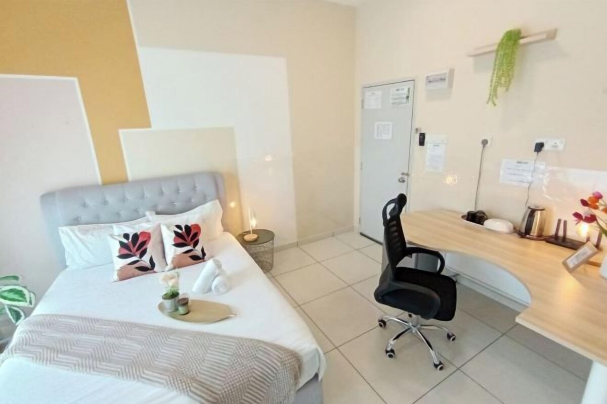Une chambre d’hôtel avec un lit, un bureau, une chaise et une petite table sur laquelle est posée une plante.