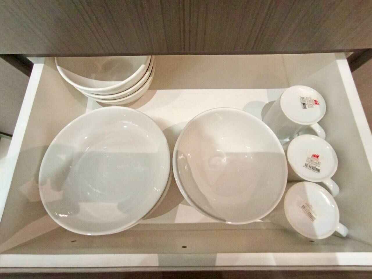Un tiroir contenant des assiettes et des tasses blanches.