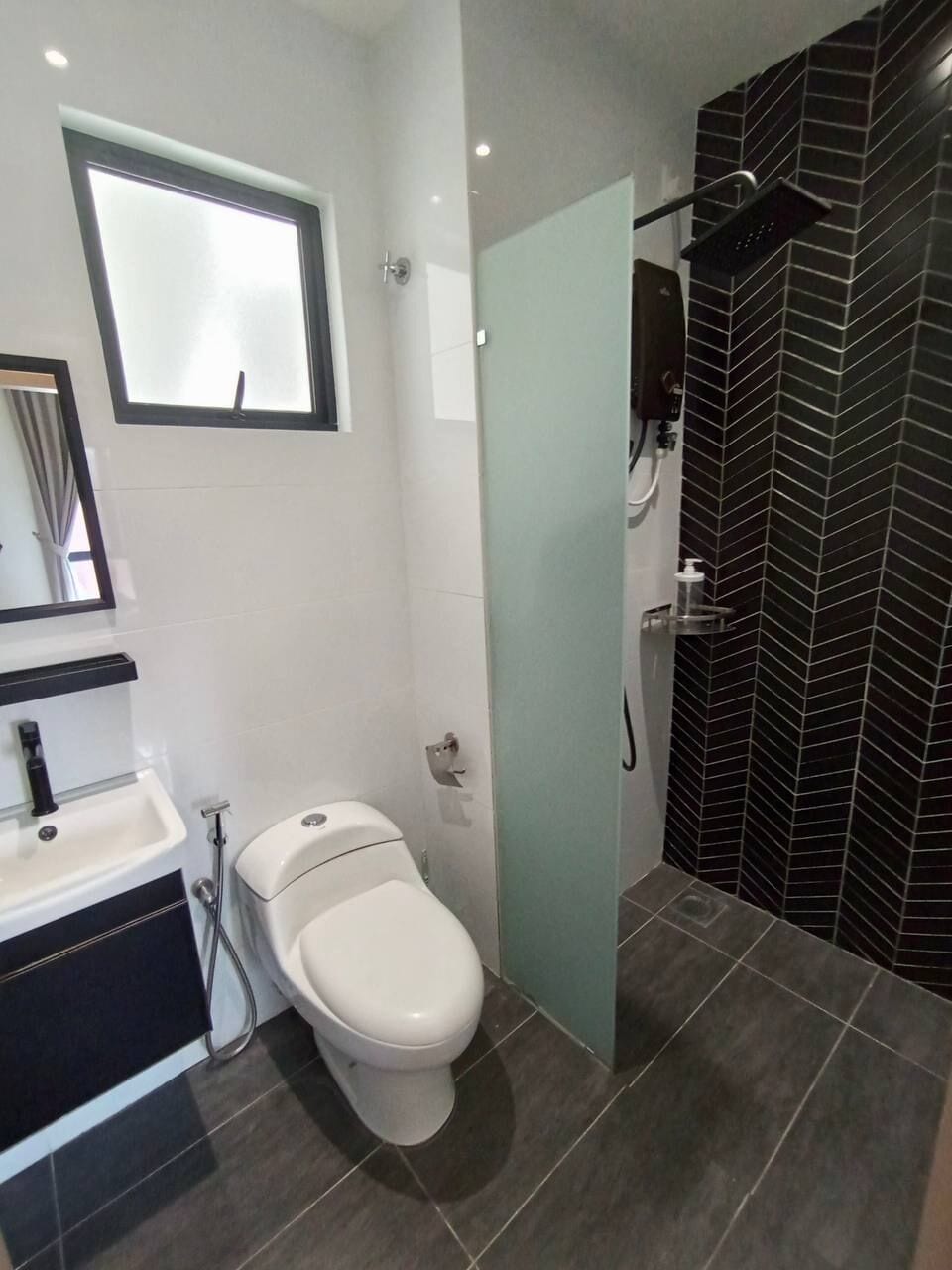 Un baño moderno con inodoro, lavabo y zona de ducha.