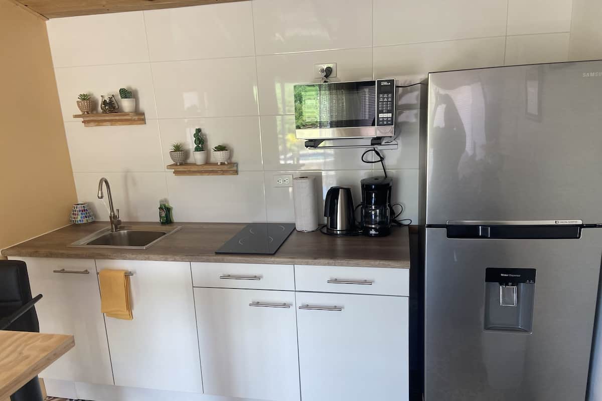 A modern kitchen with white cabinets, a stainless steel refrigerator, a microwave, and a coffee maker.