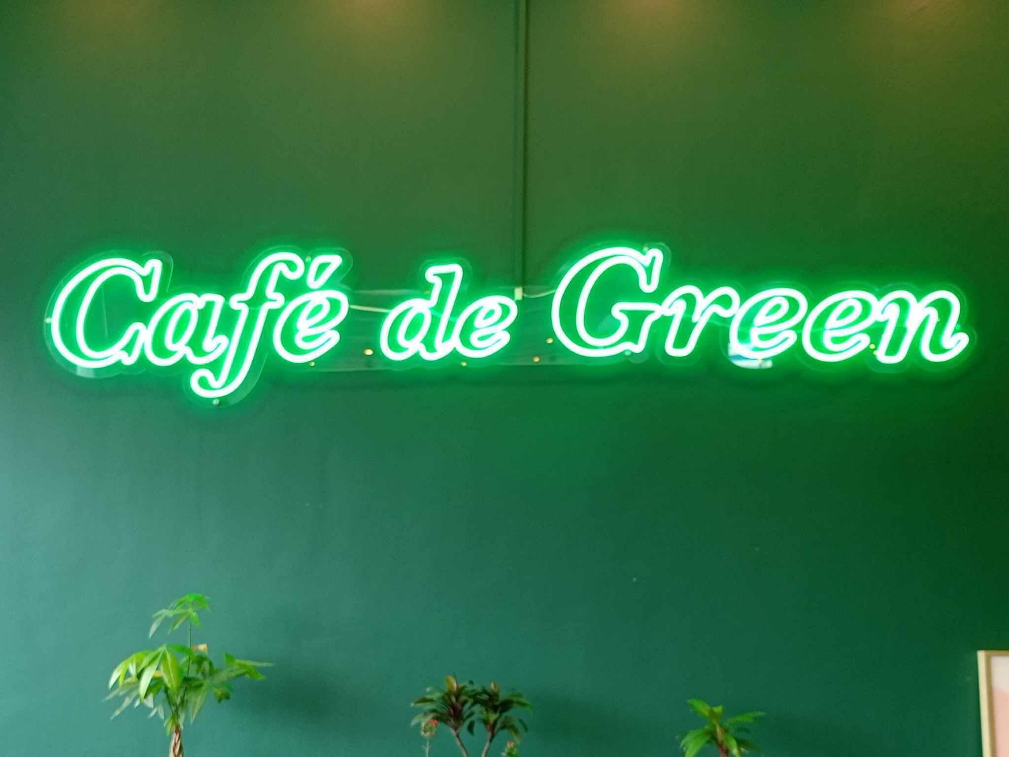 Un letrero de neón que dice 'Café de Green' sobre una pared verde.