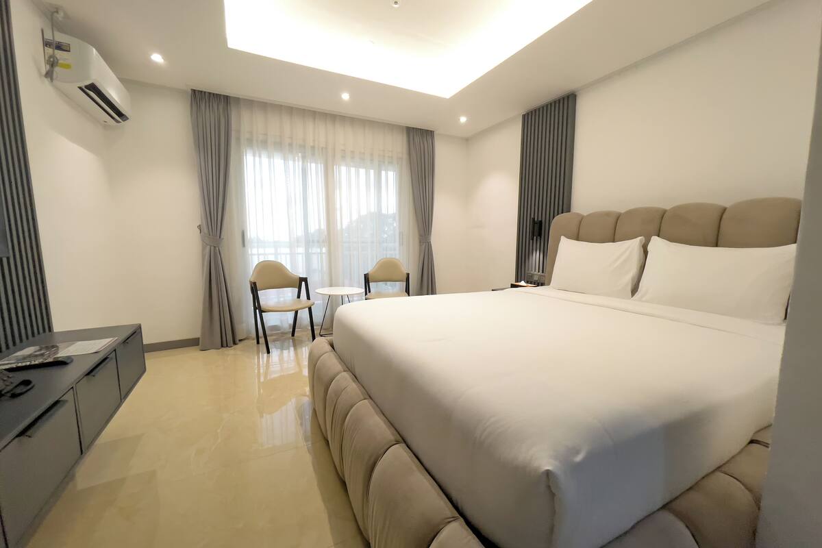 A modern hotel room with a large bed, a desk, and a chair.