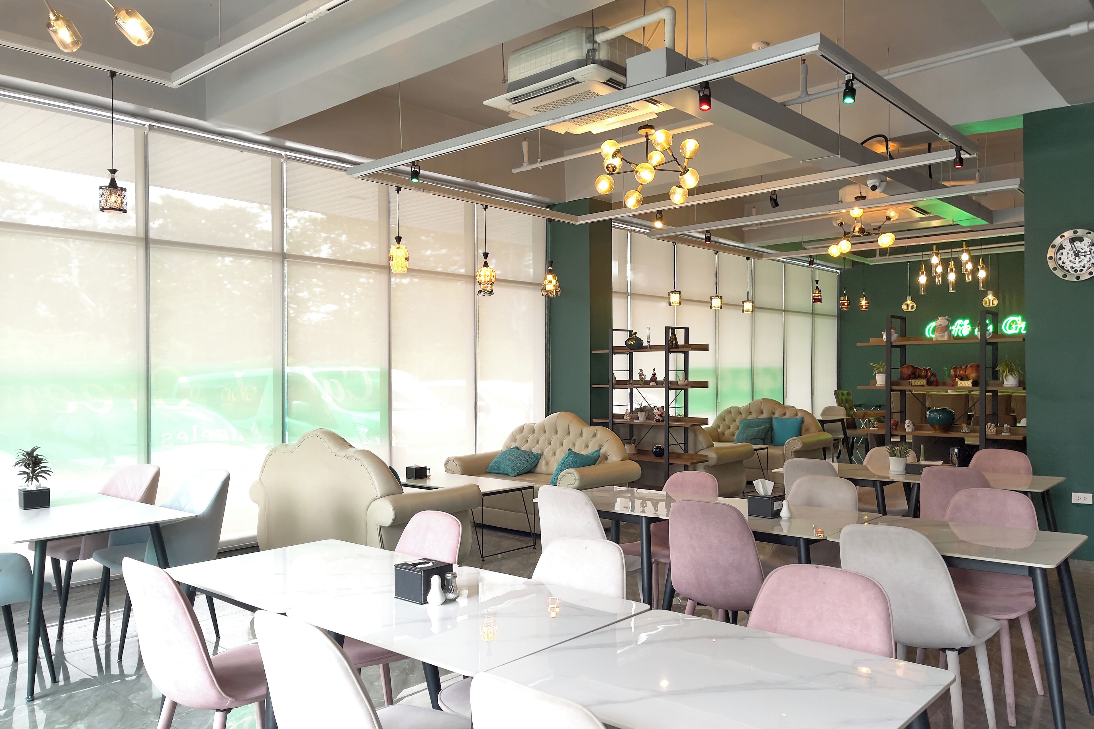 A modern cafe with a variety of seating options including tables and chairs, a sofa, and a bookshelf with decorative items.