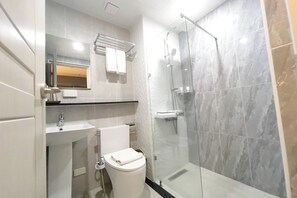 A modern bathroom with a glass-enclosed shower, a white sink, and a toilet. - The Clover Hotel Angeles City managed by Cocotel (Angeles City)
