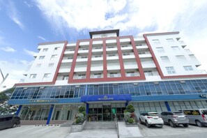 A multi-story hotel with a prominent entrance, balconies, and a parking area. - The Clover Hotel Angeles City managed by Cocotel (Angeles City)