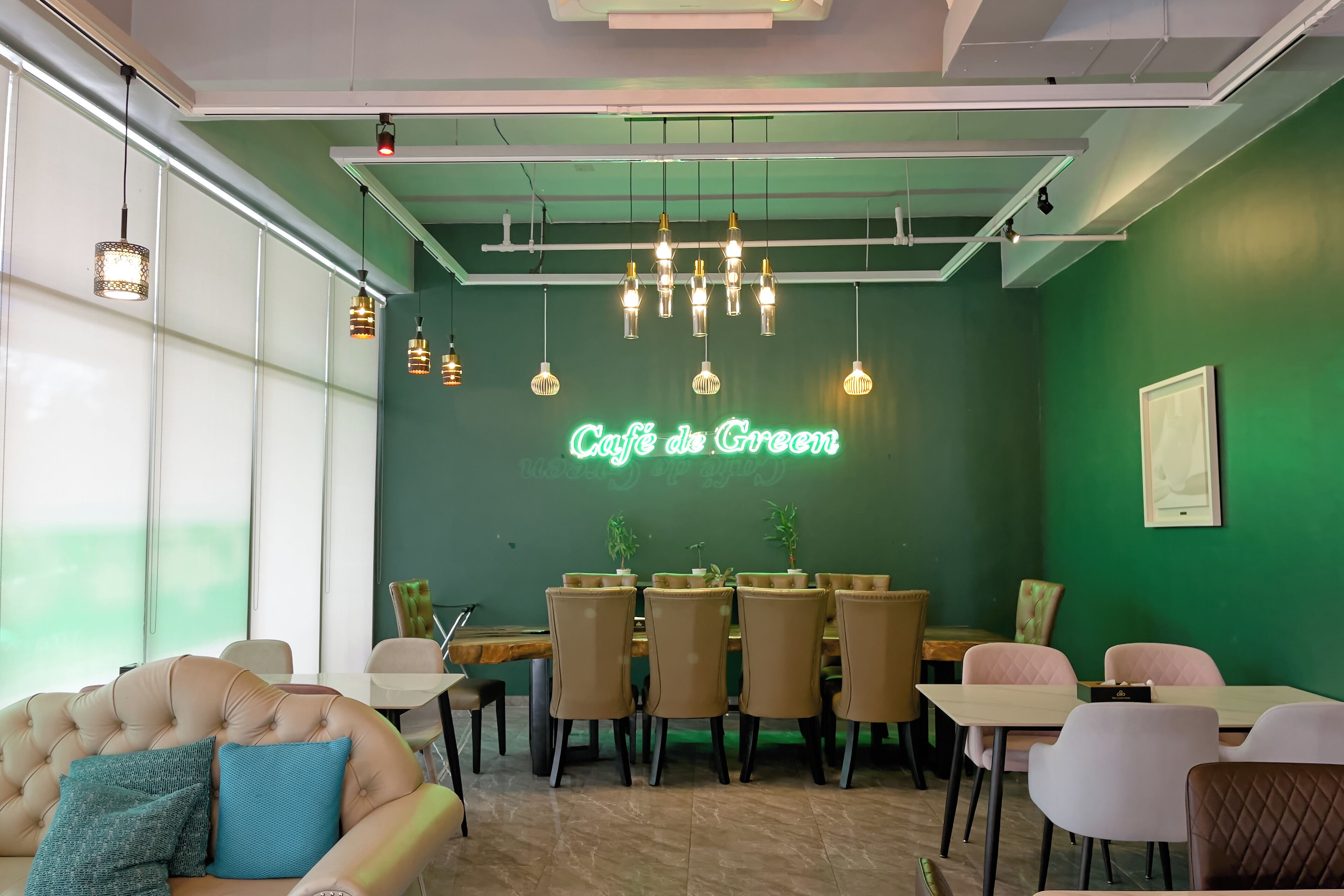 A cafe with a green wall, multiple hanging lights, and a neon sign.