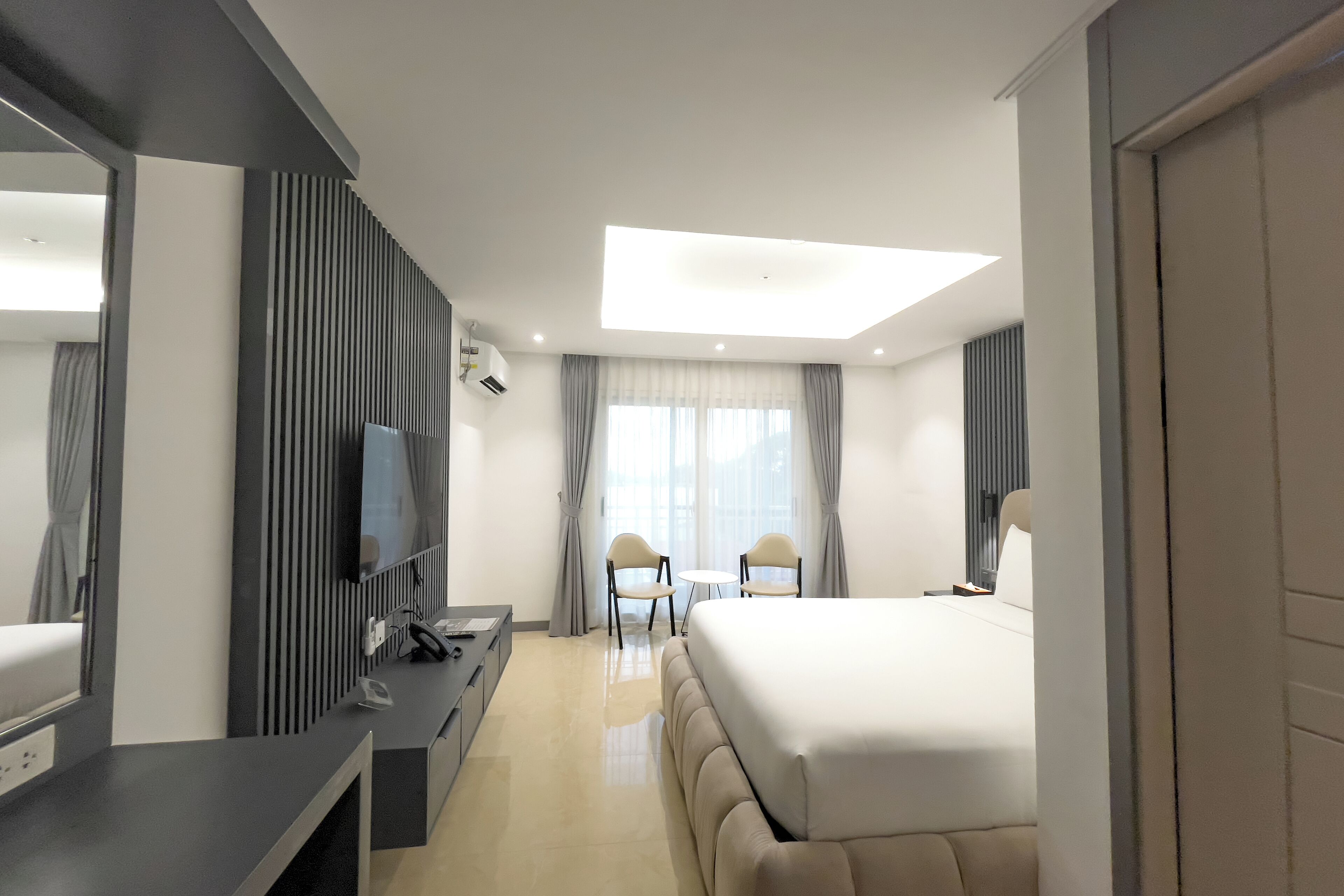 Ein modernes Hotelzimmer mit einem großen Bett, einem Schreibtisch mit Computer, einem Flachbildfernseher und einem kleinen Tisch mit Stühlen.
