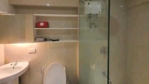 A modern bathroom with a glass-enclosed shower, a white sink, and a toilet. - Fort Victoria (Taguig)