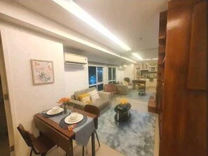 A modern living room with a dining area, a sofa, a coffee table, and a TV. - Fort Victoria (Taguig)