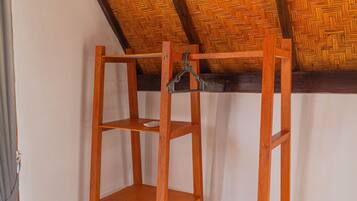 Una estanteria de fusta amb un comandament a distància, col·locada davant d'una paret amb un sostre de motius anegs.