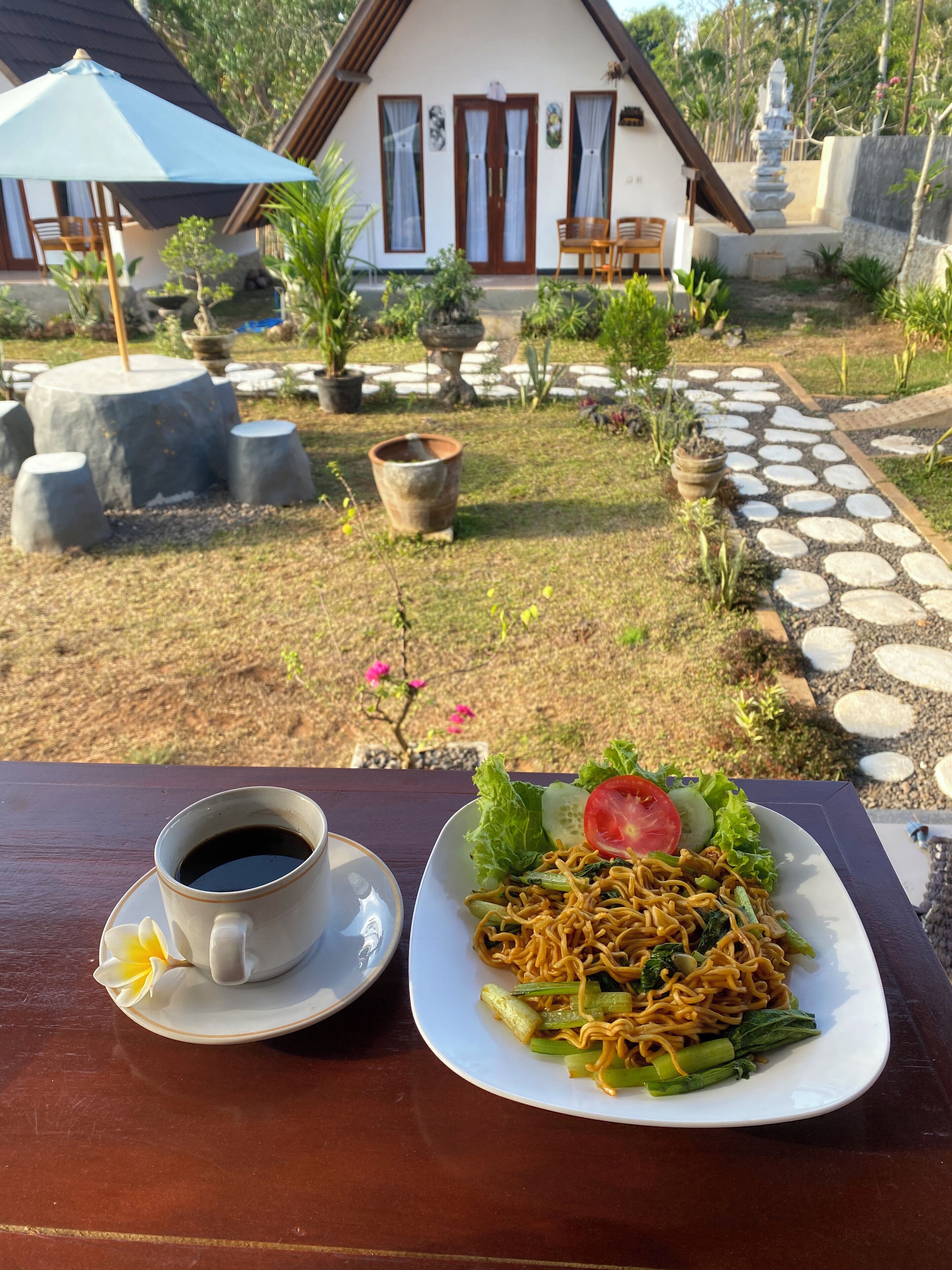 Une table à manger avec une tasse de café et une assiette de nouilles aux légumes.