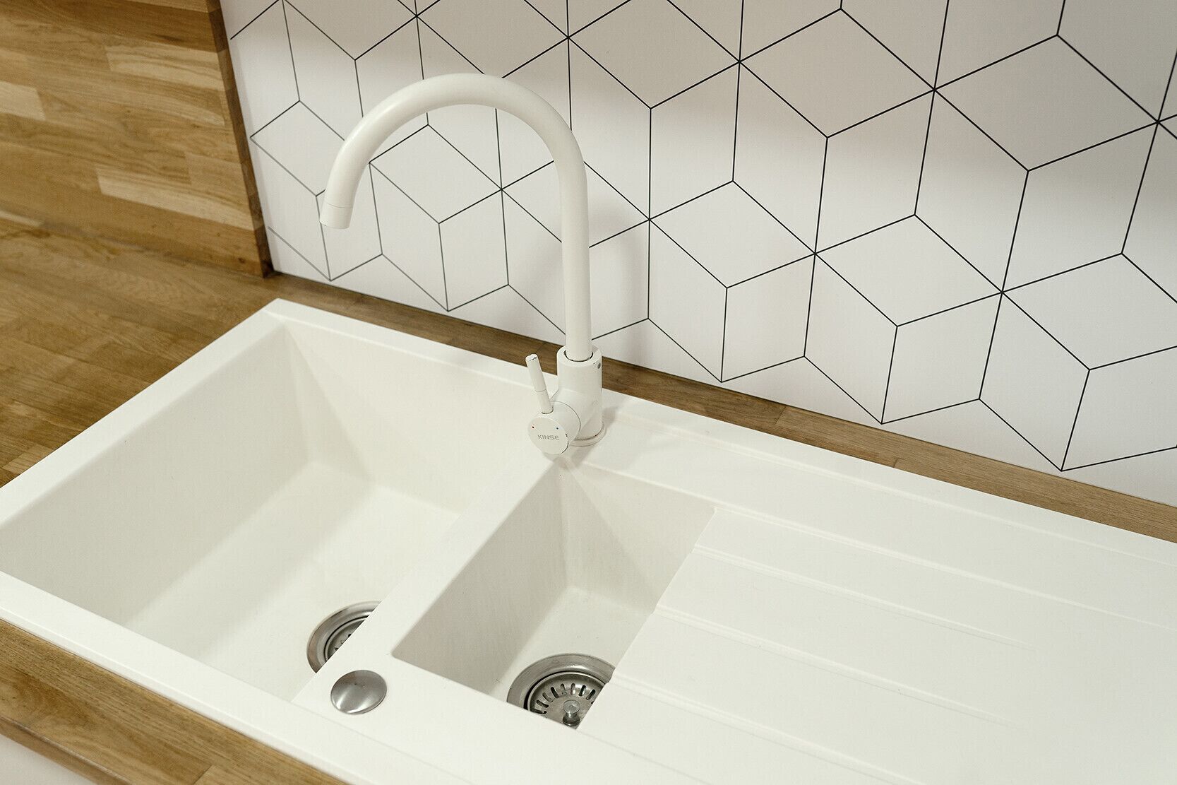 A white kitchen sink with a modern faucet, a wooden countertop, and a tiled backsplash with a geometric pattern.