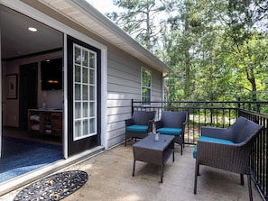 A covered patio with wicker furniture and a door leading to an interior room.
