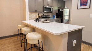 A modern kitchen with a central island, bar stools, stainless steel appliances, and a framed picture on the wall. - Archie on Old Taylor by Apex Short Term Stays (Oxford)