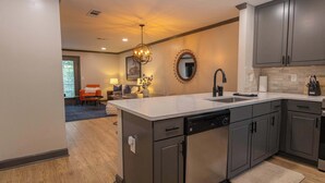 A modern kitchen with a central island, dark cabinetry, and a dining area in the background. - Archie on Old Taylor by Apex Short Term Stays (Oxford)
