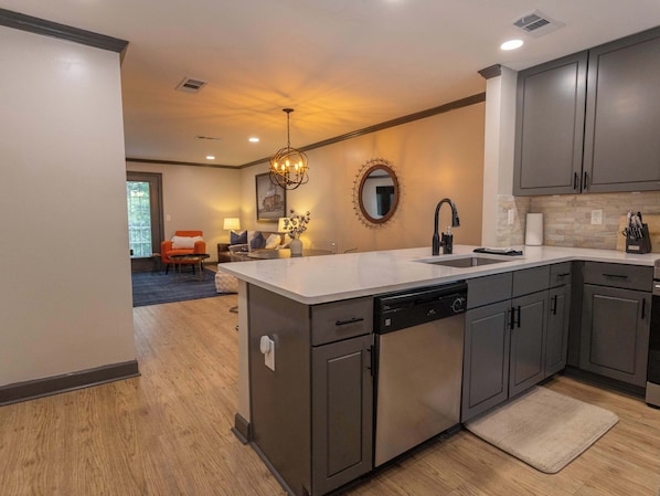 A modern kitchen with a central island, dark cabinetry, and a dining area in the background.