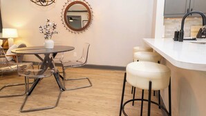 A modern kitchen with a round dining table, clear chairs, a bar stool, a pendant light, and a mirror on the wall. - Archie on Old Taylor by Apex Short Term Stays (Oxford)