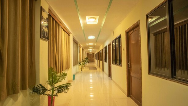 Een hotelgang met een lange corridor, deuren aan beide zijden en een plafondlamp.