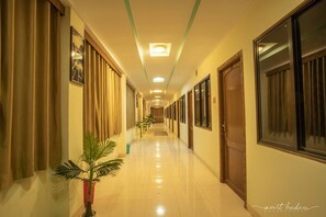 A hotel hallway with a long corridor, doors on both sides, and a ceiling light. - Hotel Dollar (Bhuj)