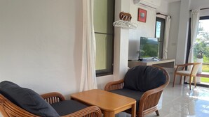 Habitación con mobiliario de mimbre, televisor de pantalla plana y vistas al exterior.