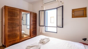 A hotel room with a large wardrobe, a bed with white linens, and a window with curtains. - Allenby Artsy Stay by Sea N' Rent (Tel Aviv)
