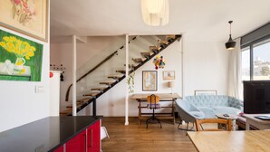 A modern living room with a staircase, a dining area, and a large window. - Allenby Artsy Stay by Sea N' Rent (Tel Aviv)