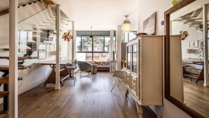 A spacious room with a wooden floor, a large mirror, and a dining area with a table and chairs. - Allenby Artsy Stay by Sea N' Rent (Tel Aviv)