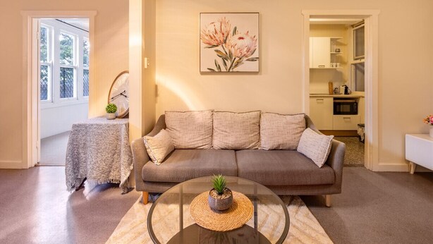 A living room with a sofa, a coffee table, and a painting on the wall. - Comfort 1-Bedroom Cottage Retreat @Yeronga (Yeronga)