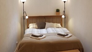 A bed with a wooden headboard, two bedside lamps, a bedside plant, and a bench at the foot of the bed. - Holiday Apartment "Haus Weitblick 2" near Slopes with Private Terrace & Wi-Fi (Hochrindl)