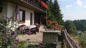 A building with a balcony, outdoor seating, and a stone wall. - Holiday Apartment "Haus Weitblick 2" near Slopes with Private Terrace & Wi-Fi (Hochrindl)