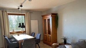 A dining area with a table and chairs, a wooden cabinet, a sofa, and a window with curtains. - Holiday Apartment "Haus Weitblick 2" near Slopes with Private Terrace & Wi-Fi (Hochrindl)