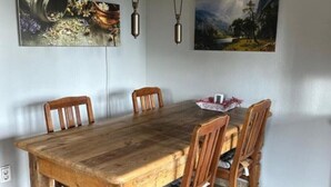 Un coin repas avec une table et des chaises en bois, deux lampes suspendues et deux tableaux encadrés accrochés au mur.
