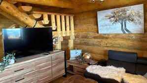 A wooden interior with a TV, wooden wall decor, a painting, and a sofa. - Chalet "Reimers 2a" with Mountain View, Private Terrace & Wi-Fi (Hochrindl)