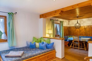 Une pièce chaleureuse avec un banc, un plafond en bois et un coin repas.
