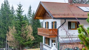 Una casa de dos pisos con un balcón, una chimenea y un pequeño horno al aire libre.