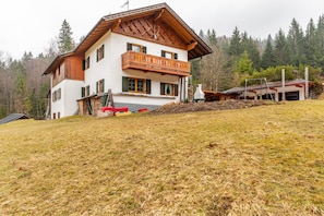 Un chalet à deux étages doté d’un balcon en bois, d’un télésiège et surplombant un paysage montagneux.