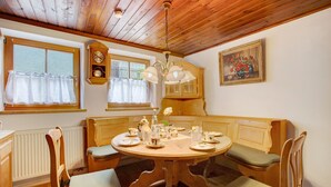 A dining area with a wooden table, chairs, a clock, and a painting on the wall.