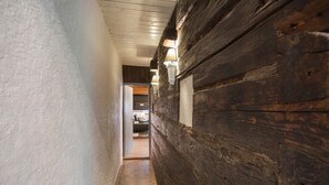 A narrow hallway with wooden walls and a door leading to a room.