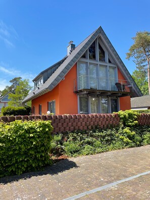 A house with a sloped roof, large windows, and a brick wall.