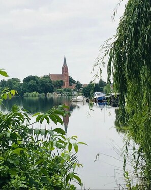Un lac paisible, avec une église et des bateaux, entouré de verdure.