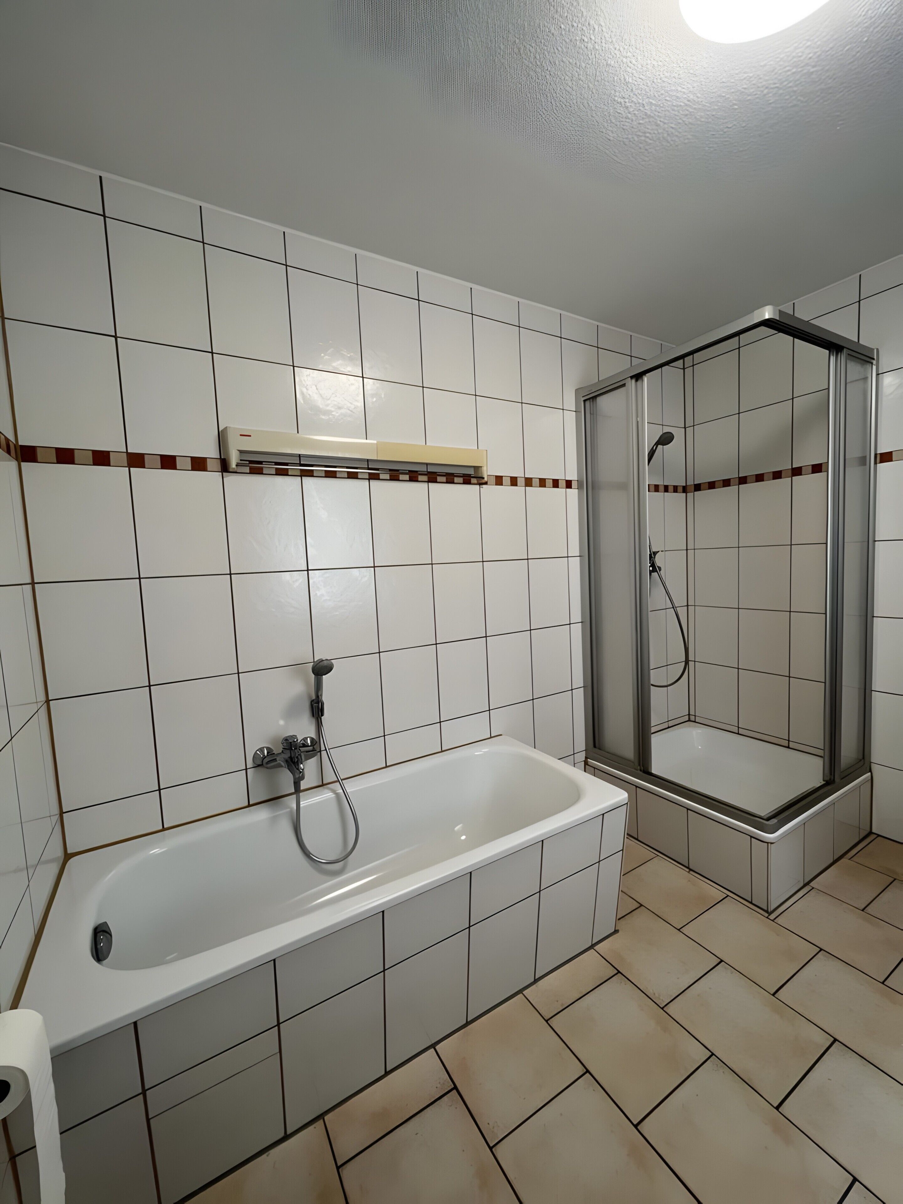 Ein Badezimmer mit einer Badewanne, einer Duschkabine und einer Fliesenwand.