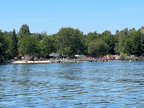 Un parc au bord du lac, avec un quai, des arbres et des gens.
