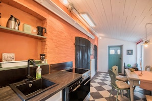 Une cuisine avec un évier noir, une cuisinière en acier inoxydable et un carrelage à motifs.