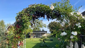 A garden with a white picket fence, a lawn, and a building in the background. - Holiday Home 'Teehaus' (Saal)