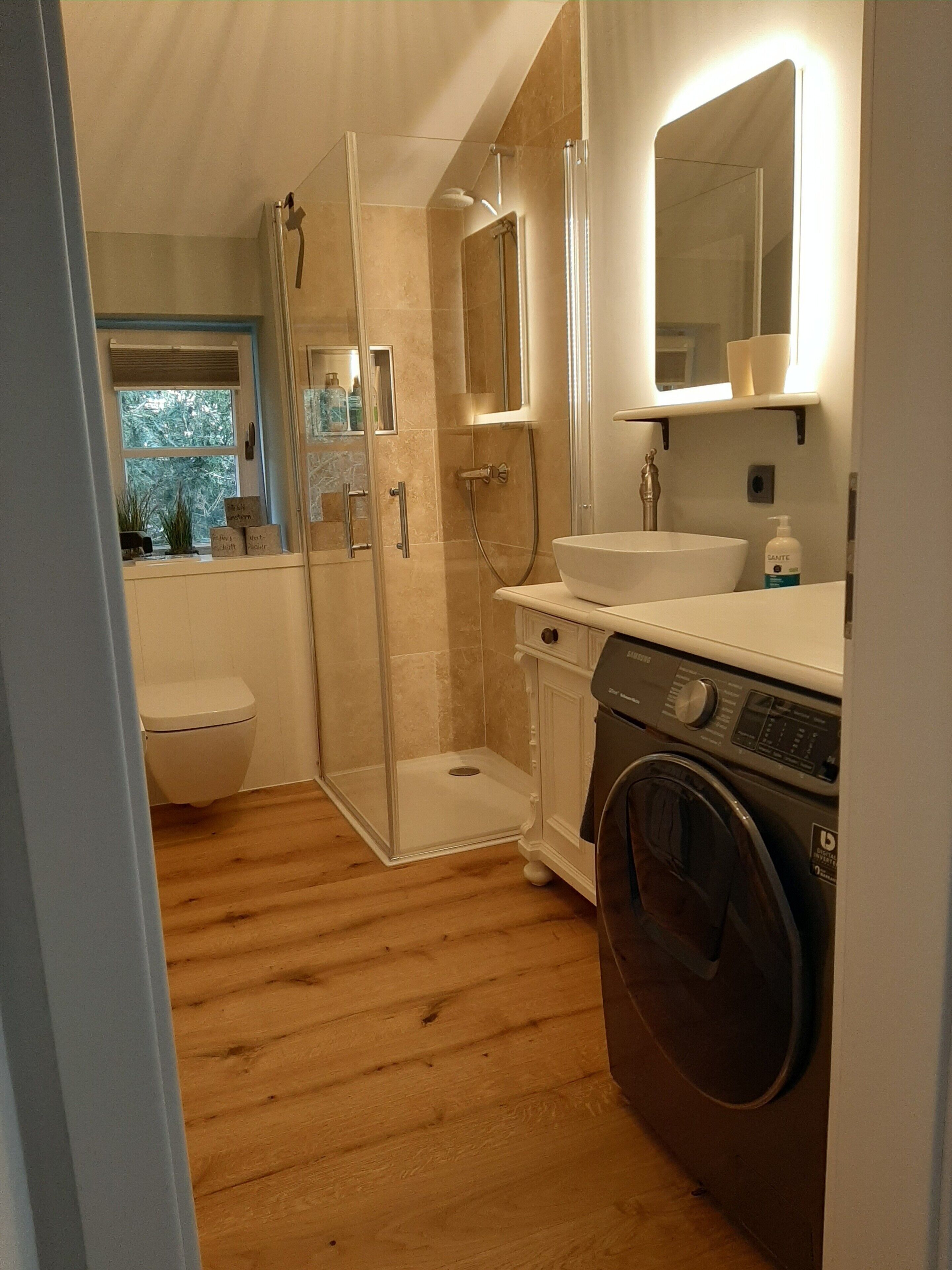 Un baño con ducha, inodoro, lavamanos y lavadora.