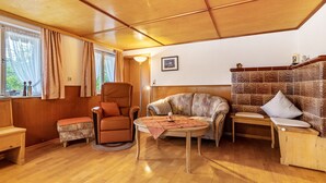 A cozy room with a wooden ceiling, a sofa, a chair, a small table, and a bench.