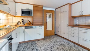 A kitchen with white cabinets, a microwave, a toaster, and a tiled floor.